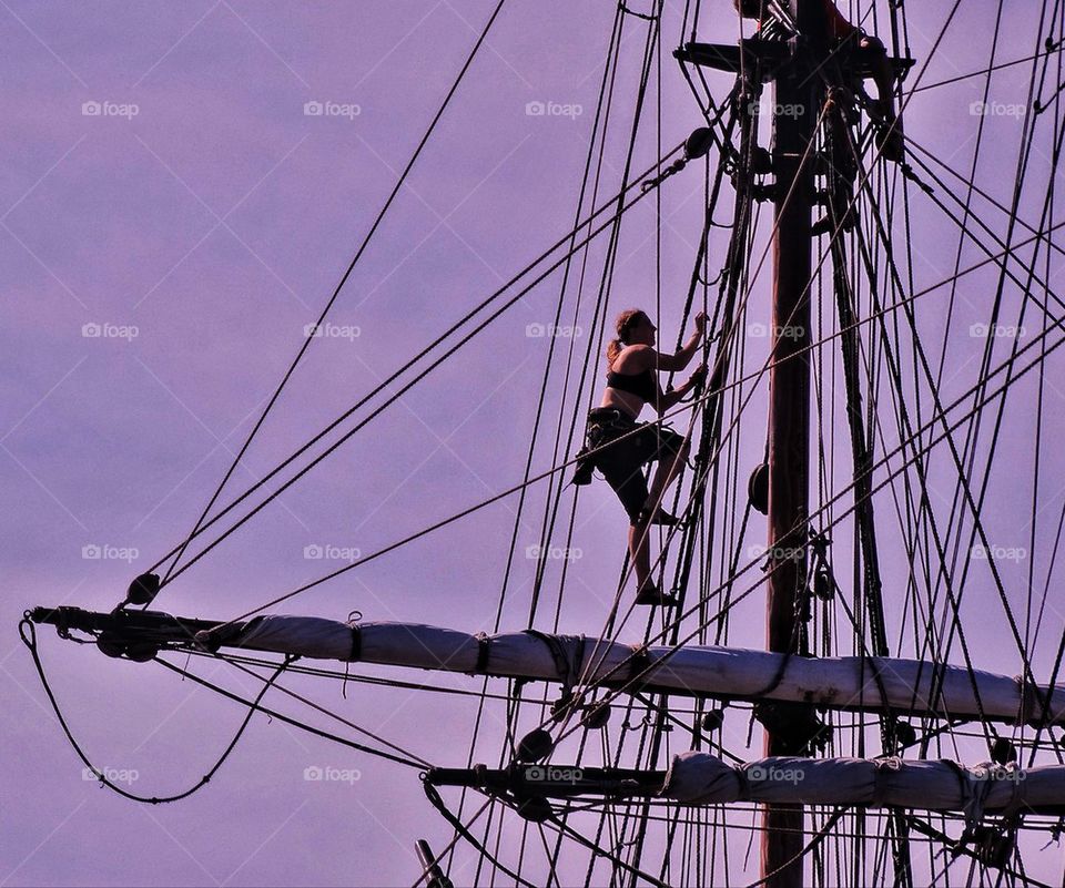 Sailor climbing rigging of a tall ship
