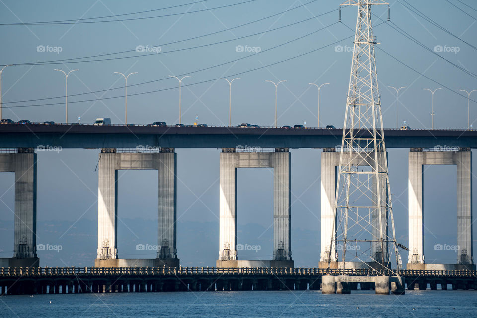 Car on bridge over sea with electric pylon