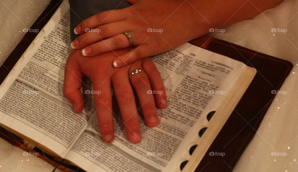 Wedding image of hands sporting wedding rings beside bible verse couple chose to be read at ceremony 