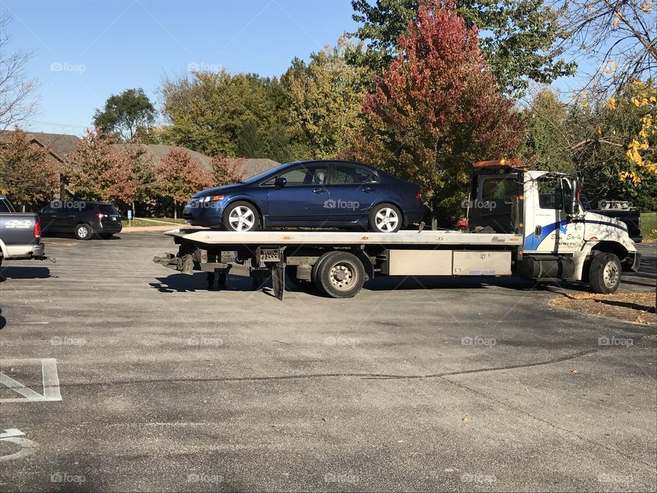 Blue car loaded on a tow truck 