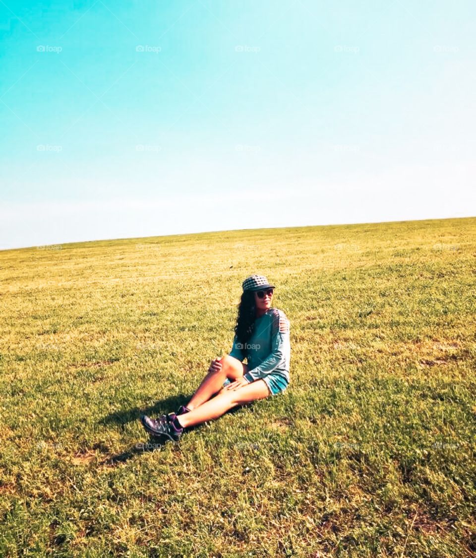 A girl is sitting on green meadow on summer morning