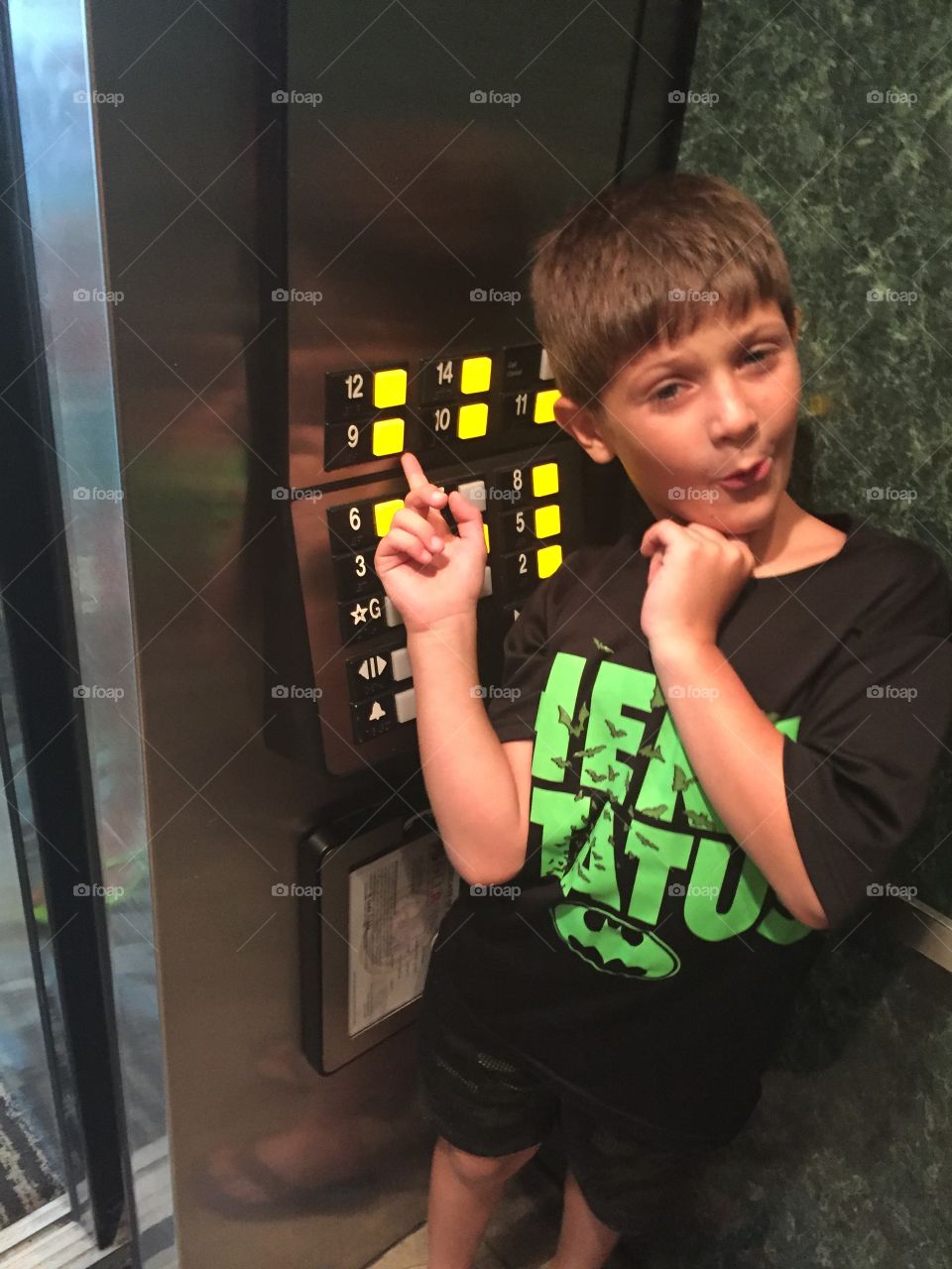 Portrait of little child gesturing towards lift numbers