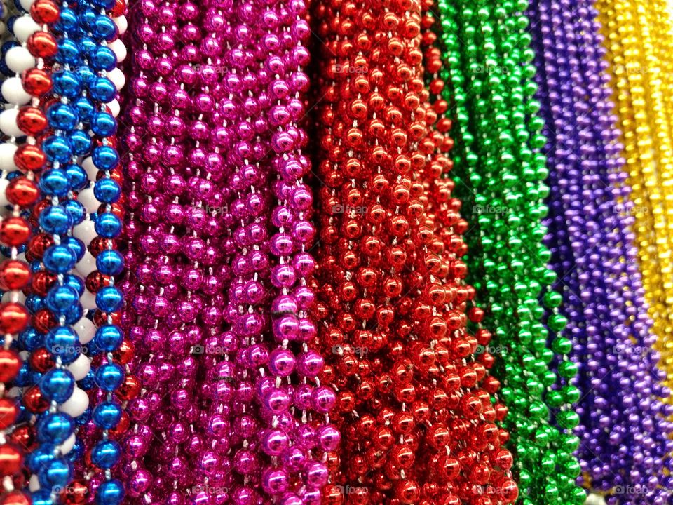 Metallic beads, necklaces. Mardi gras, party decorations, crafts, shiny, muticolor abstract texture. Red, pink, green, rainbow, fuschia