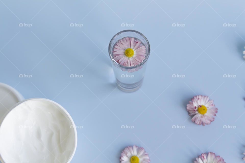 Jars with cosmetic products, beauty cosmetics in a white jar with cream and water with fragrant flowers.