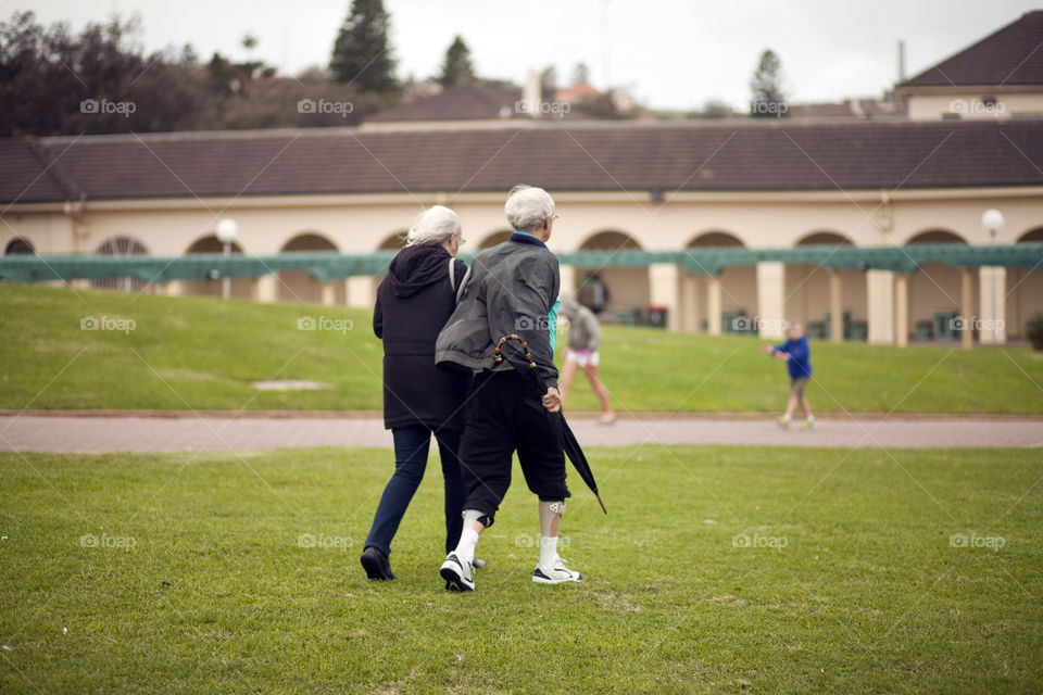 Old man and old woman, walking side by side, gray haired couple, taking a stroll at the beach park