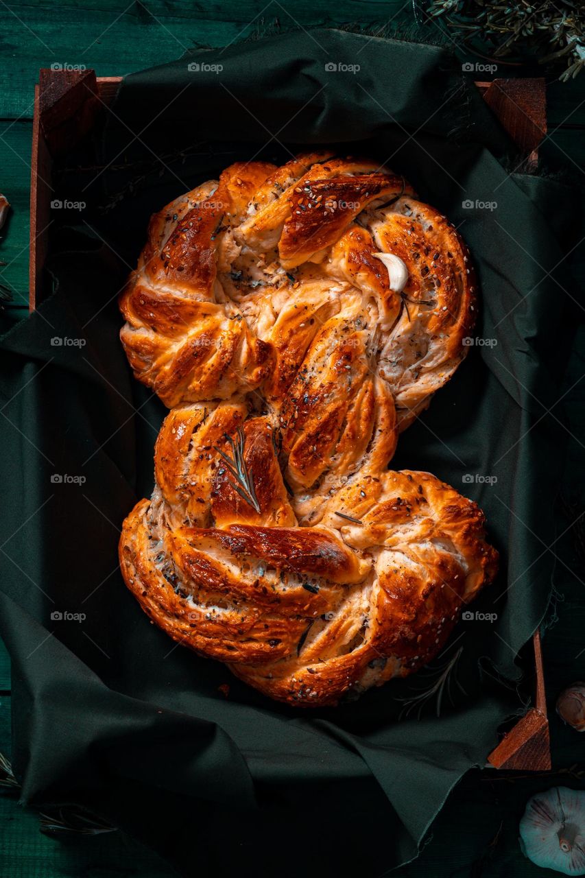 Rosemary twisted loaf bread on a green wooden background, still life, rustic style.