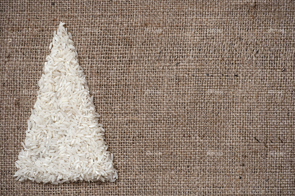 Christmas tree made of rice on sack background postcard