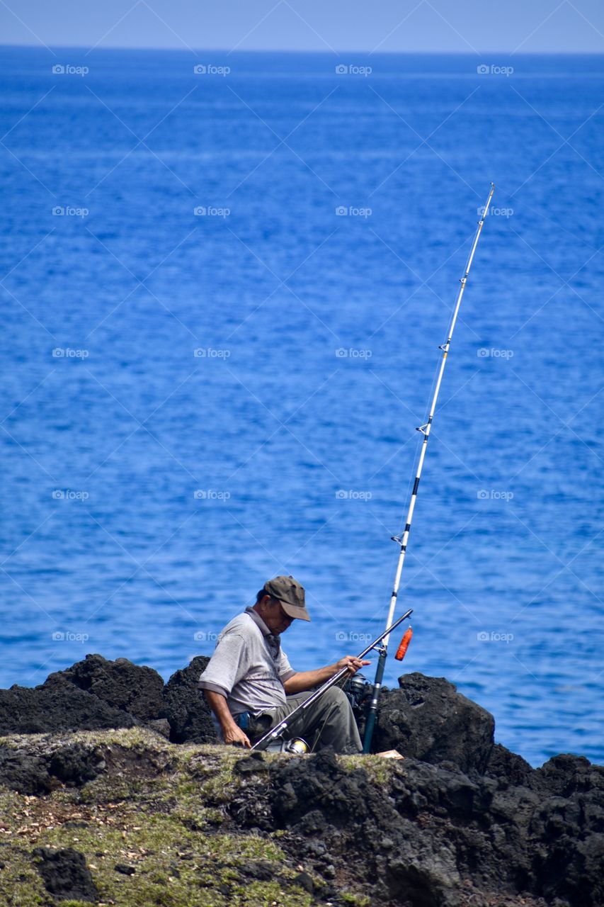 Fisherman on the sea cliffs of lava rock on the east side of the Big Island of Hawaii