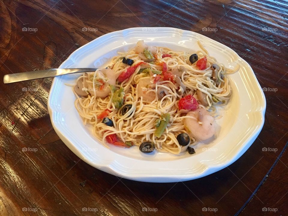 Angel hair pasta with shrimp, black olives, asparagus and tomatoes tossed in olive oil