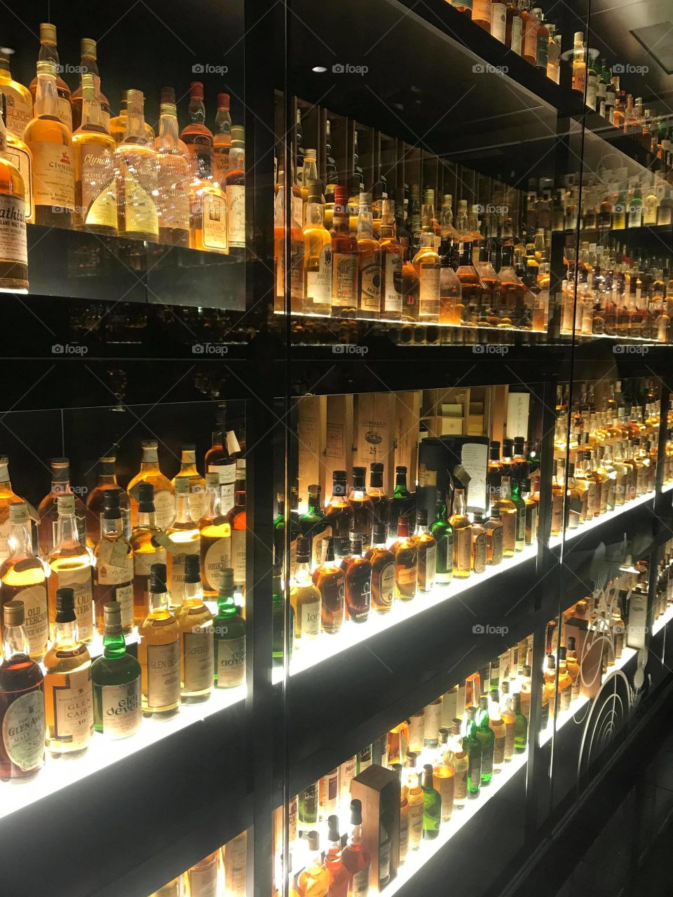 wall of brightly back lit bottles of alcohol