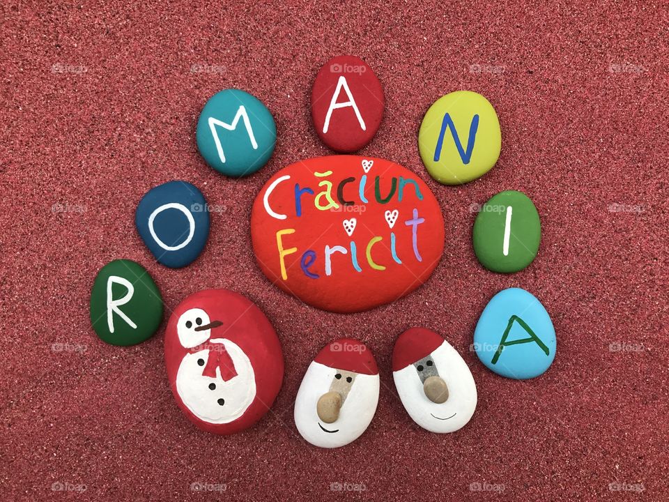 Craciun Fericit Romania, romanian Merry Christmas with colored stones over red sand 
