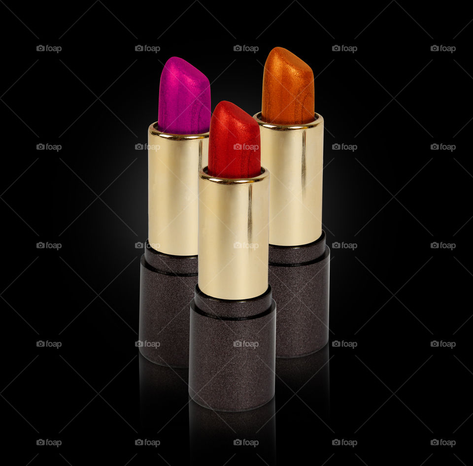 Three lipsticks on black background