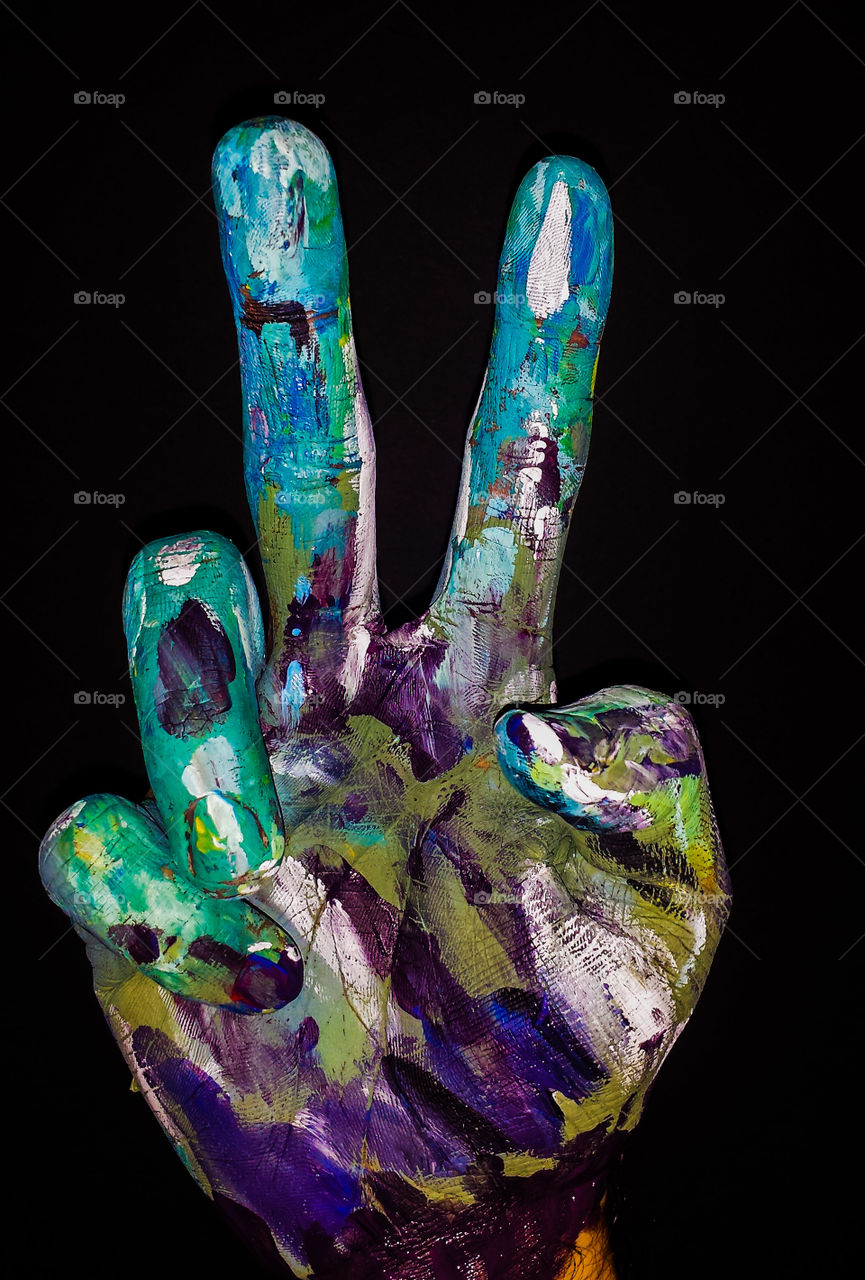 Painted hand showing v sign on black background