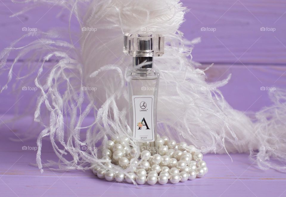 Aesthetic photo of parfum with pearls and feathers