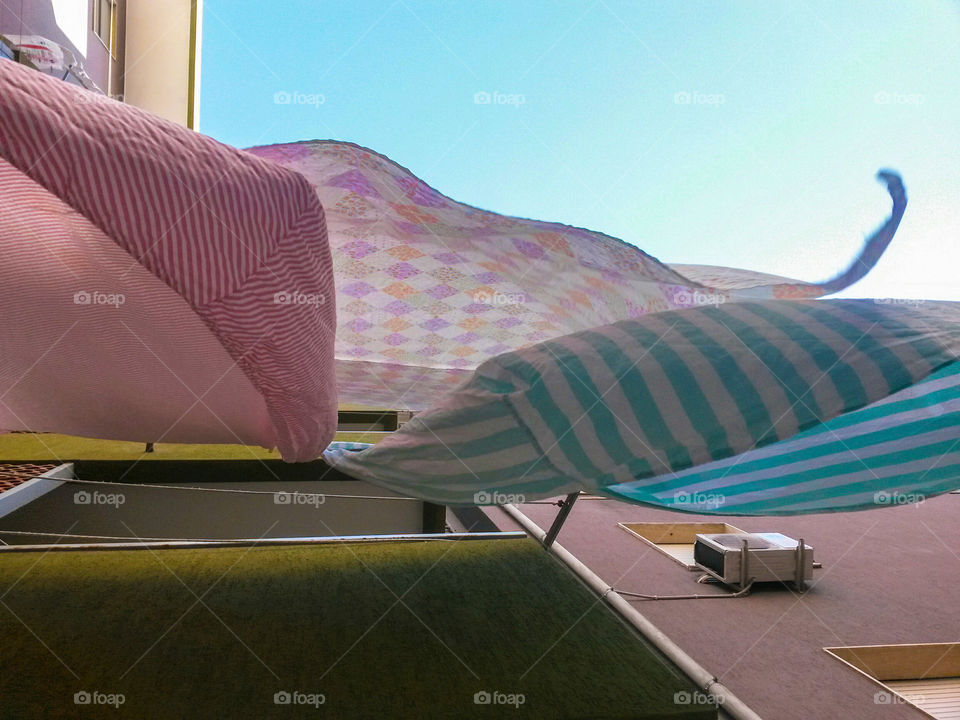 colored bed sheets drying outdoors view from below