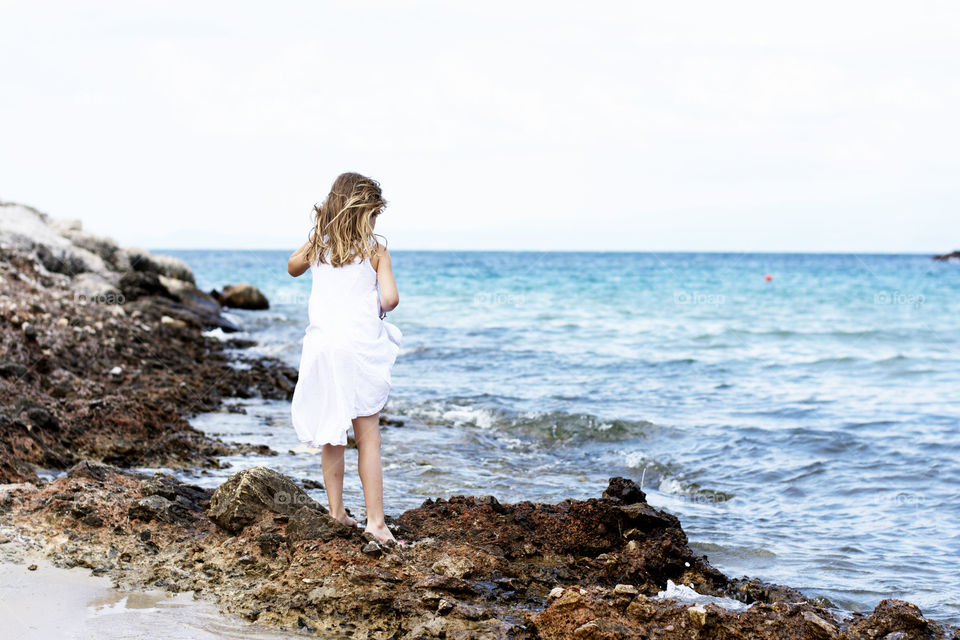 little girl on the rocks. little girl standing on the rocks at the beach