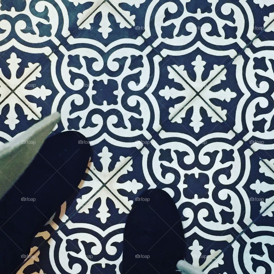 Black boots on blue and white tiled floor. 