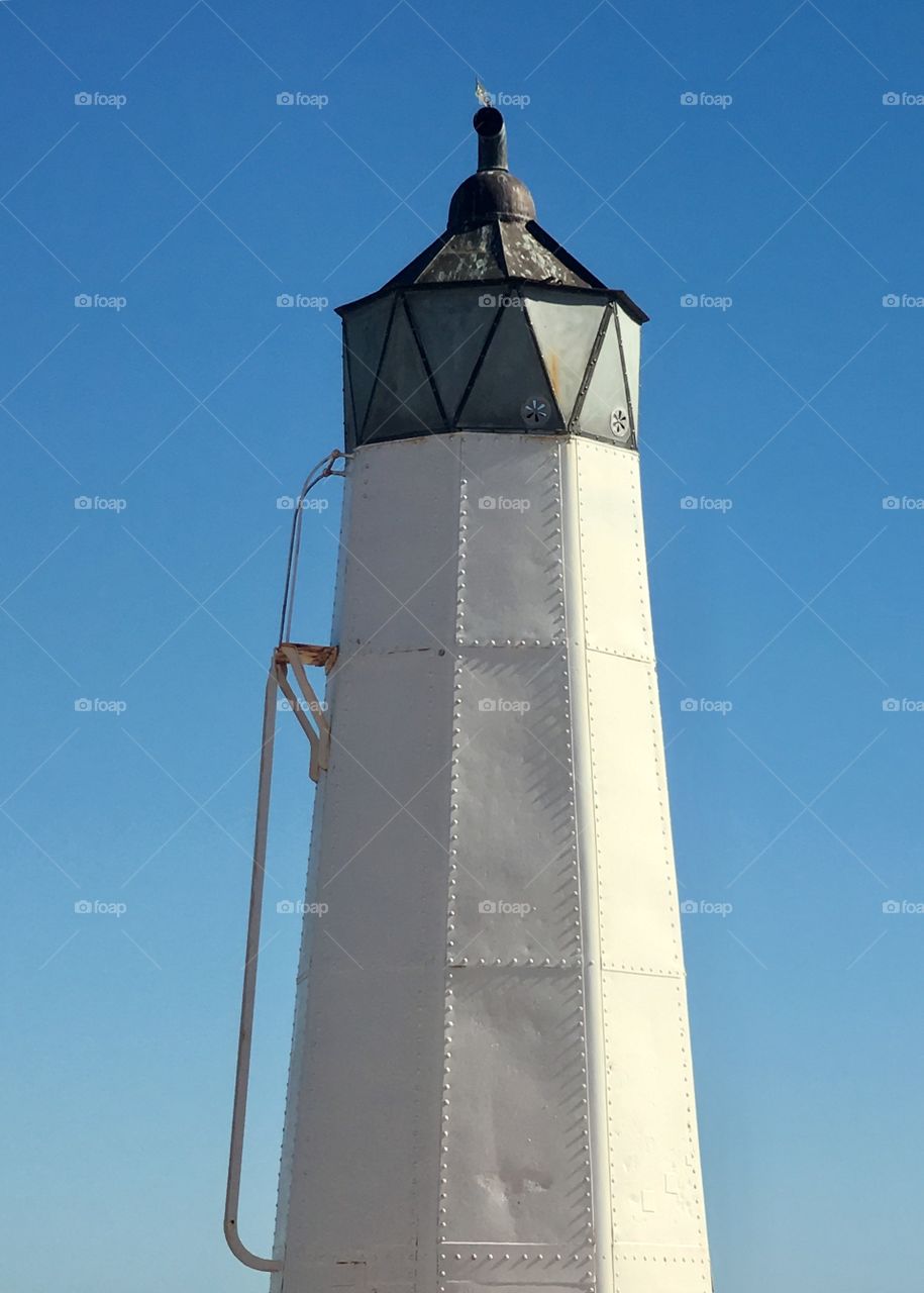 White lighthouse against a vivid blue sky, minimalist 