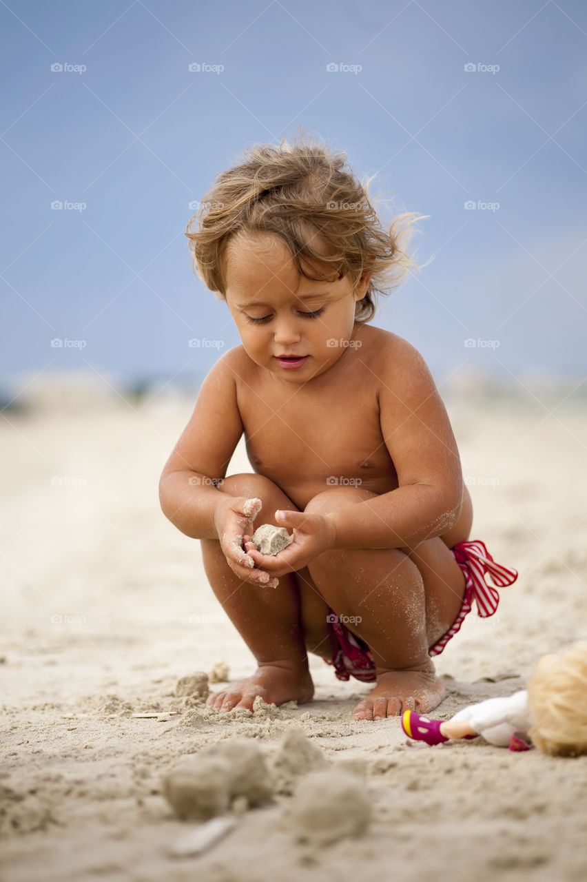 Baby Girl on the Beach Playing with Sand