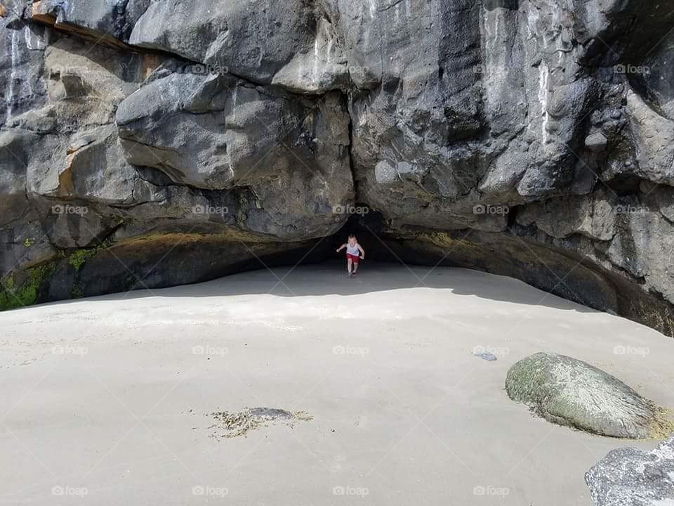 Boy emerging from a coastal cavern.
