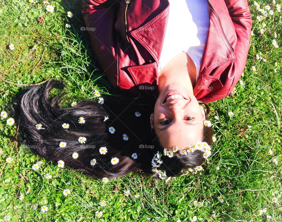 Beautiful woman lying on grass with white flowers on hair