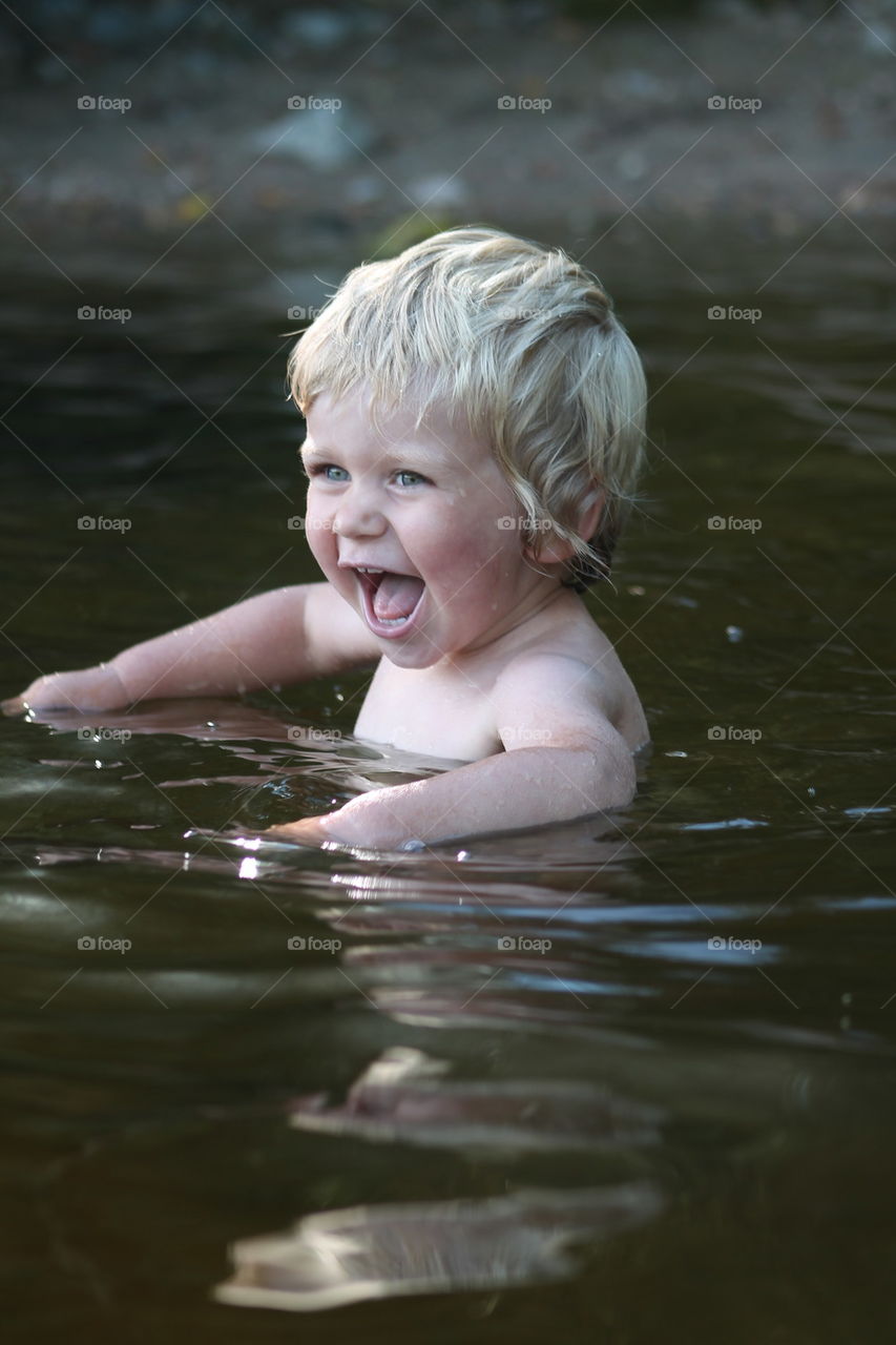 Laughing little boy playing in water
