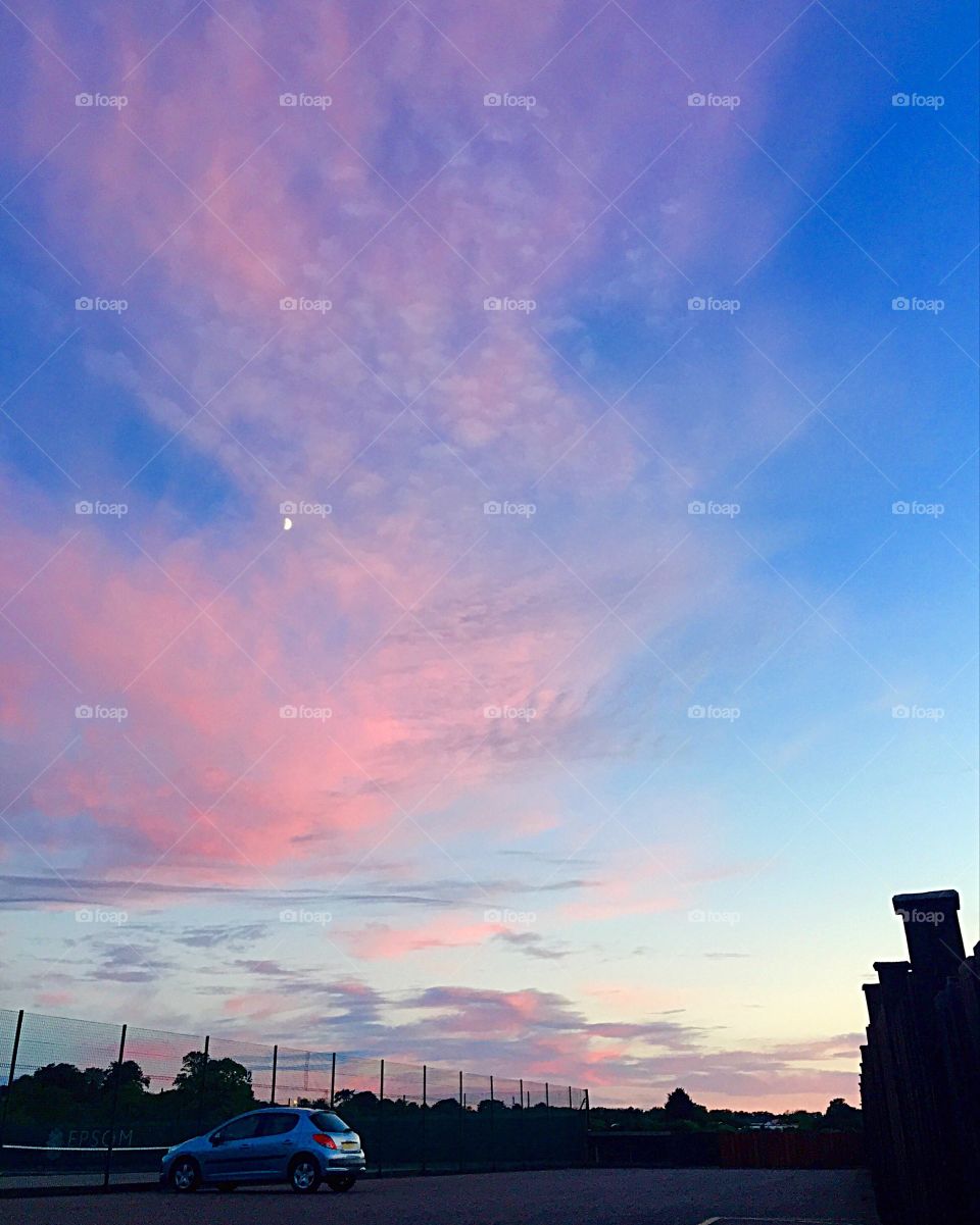 Beautiful blue and pink sunset, with the small glow of the moon in British autumn time. Stunning cloud patterns and colours created by the fading sun!