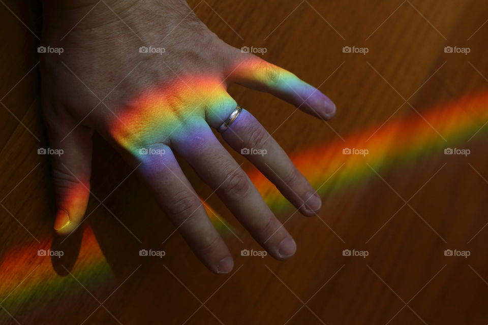 Hands with engagement ring and rainbow celebrating Lgbt gay marriage
