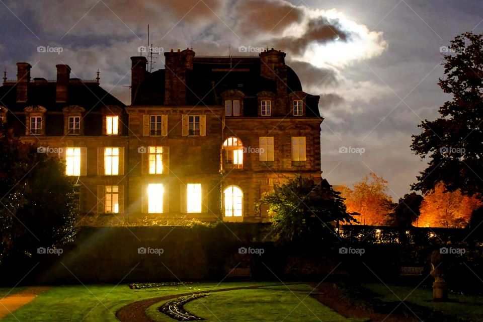 View of the illuminated windows and the garden of Vannes' prefecture at night