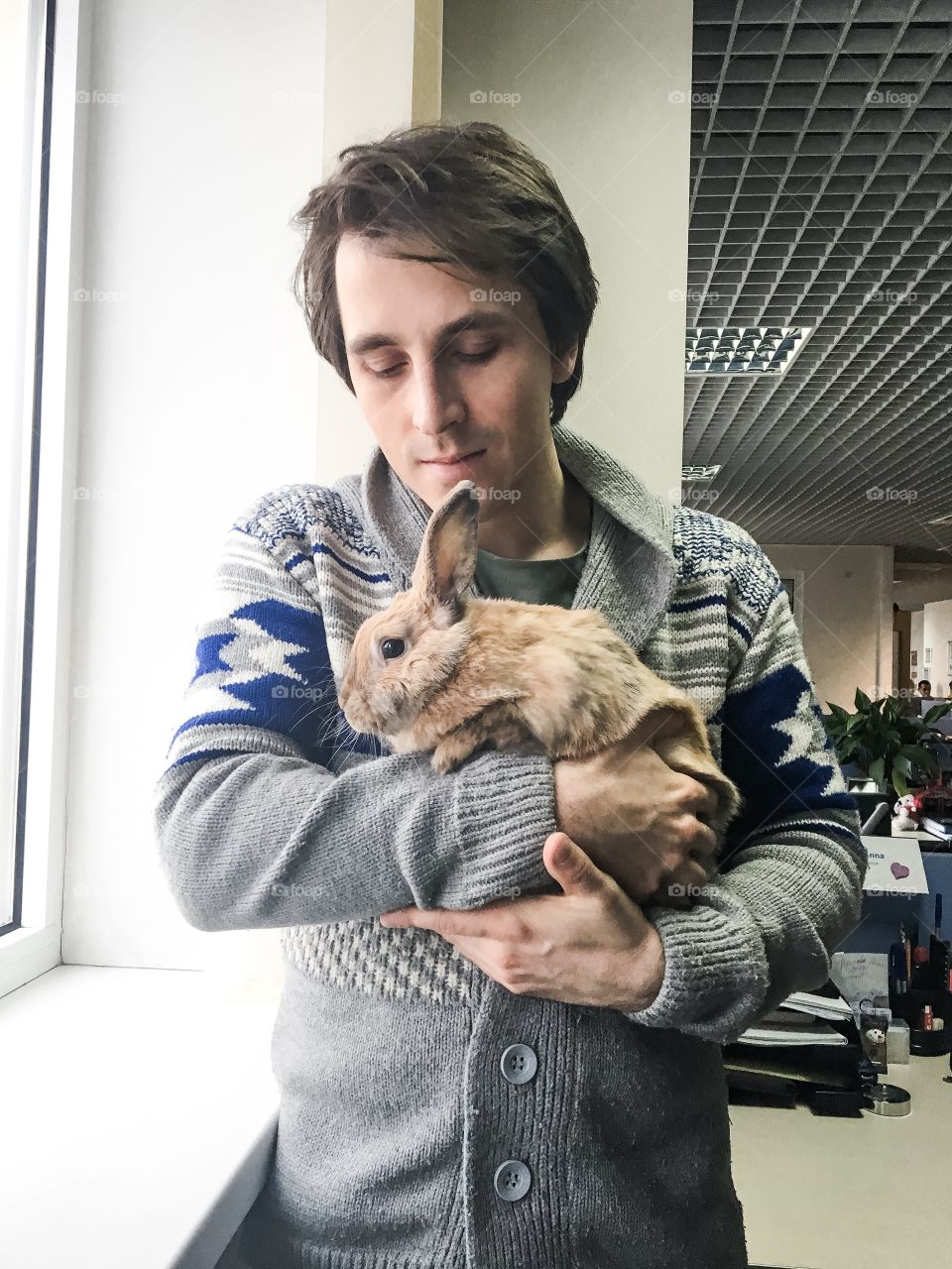 Man hugging fluffy rabbit in office