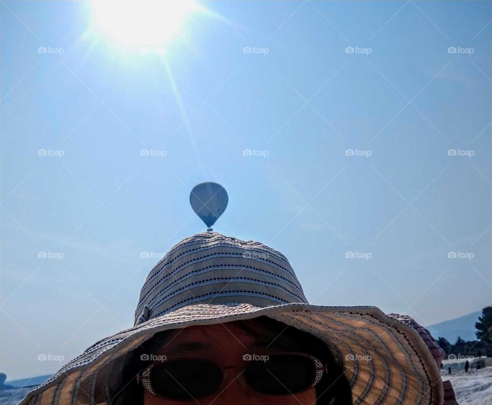 A very interesting photo. the sun shines on the hat of a lady, and just a hot air balloon in the distance stayed on her hat.
the photo timing is perfect. wonderful!
