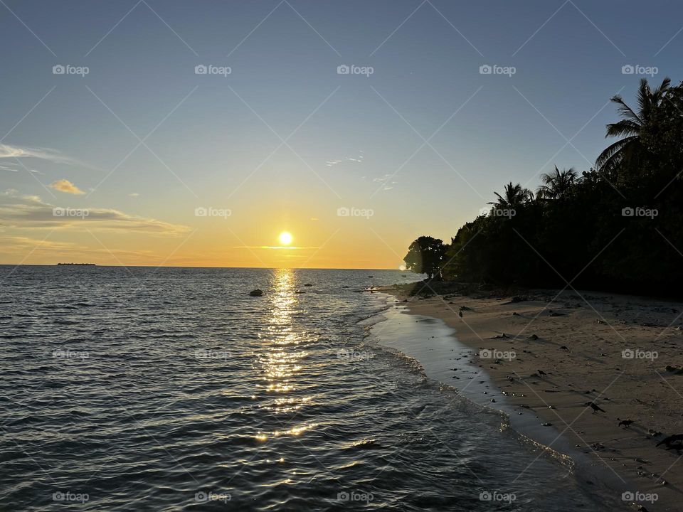 Thaa atoll Veymamdoo beach just moments before sunset. The sun bids goodbye by reflecting its golden rays on the crystal clear lagoon.