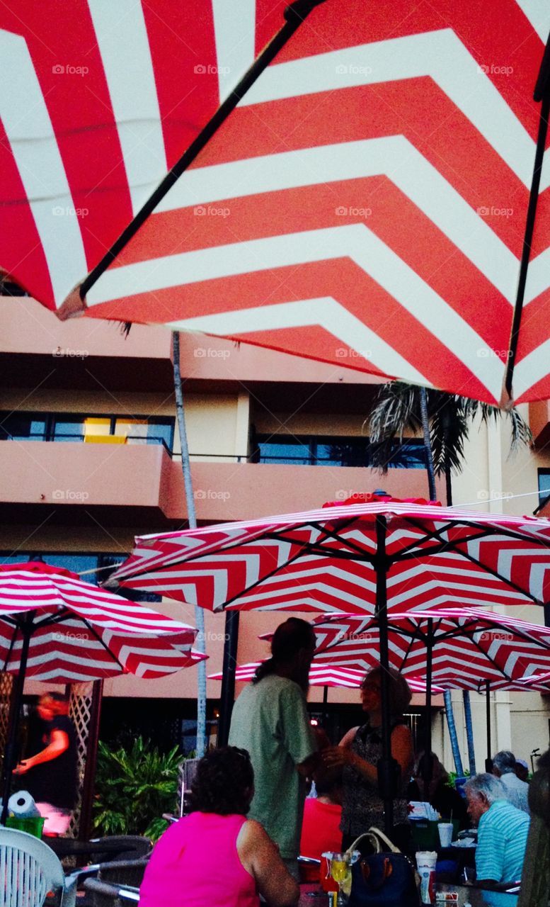 Outdoor restaurant with tables and pretty striped umbrellas. People are in the shade!