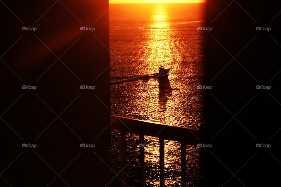 From a vantage point seen from inside a hotel room in Atlantic City, a sailboat crosses into the brilliant light of beautiful sunrise off the Atlantic.