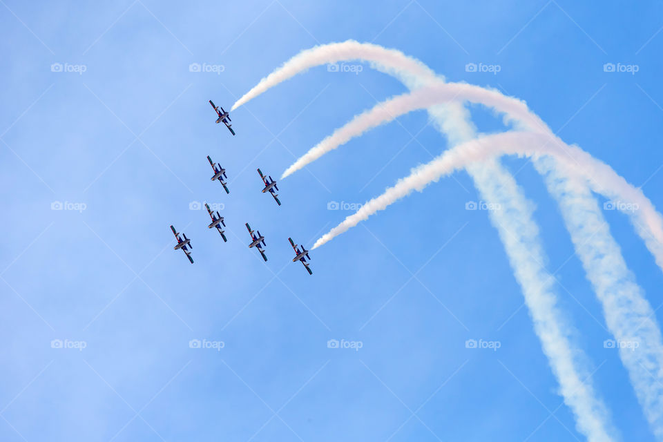 Seven planes are flying above in the blue sky