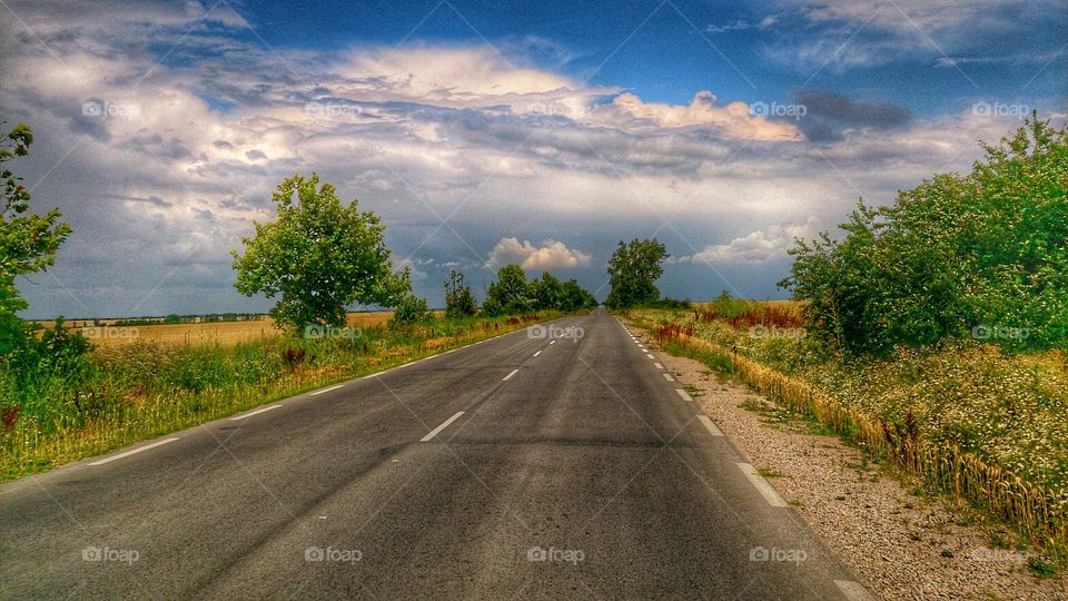Empty road against cloudy sky