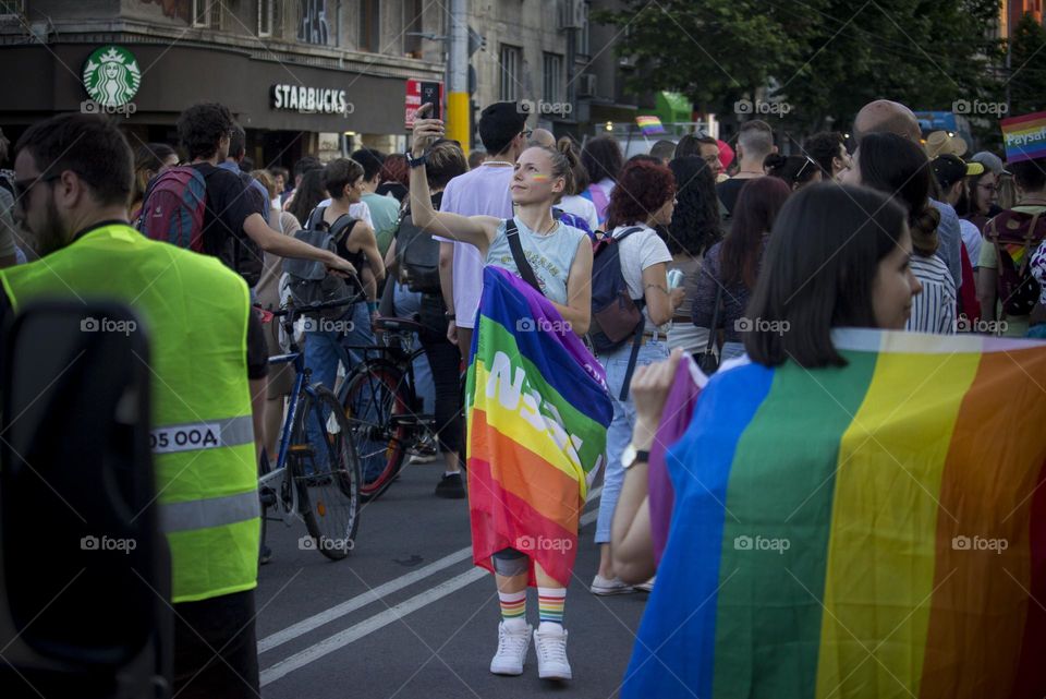 People in the Pride festival, a woman in rainbow flag at the street