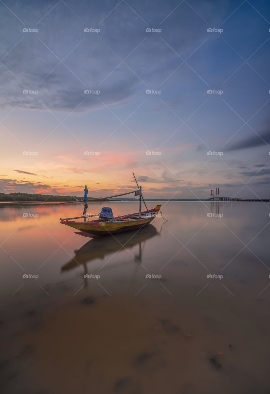 lonely boat during sunset around suramadu bridge