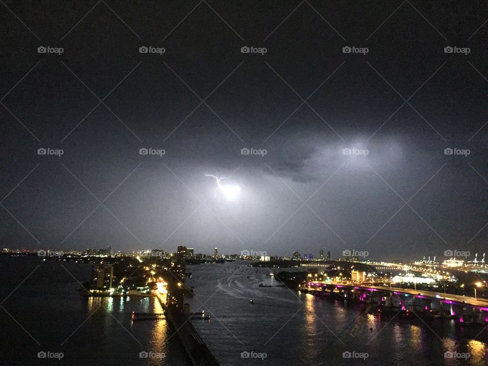View of illuminated city during storm clouds