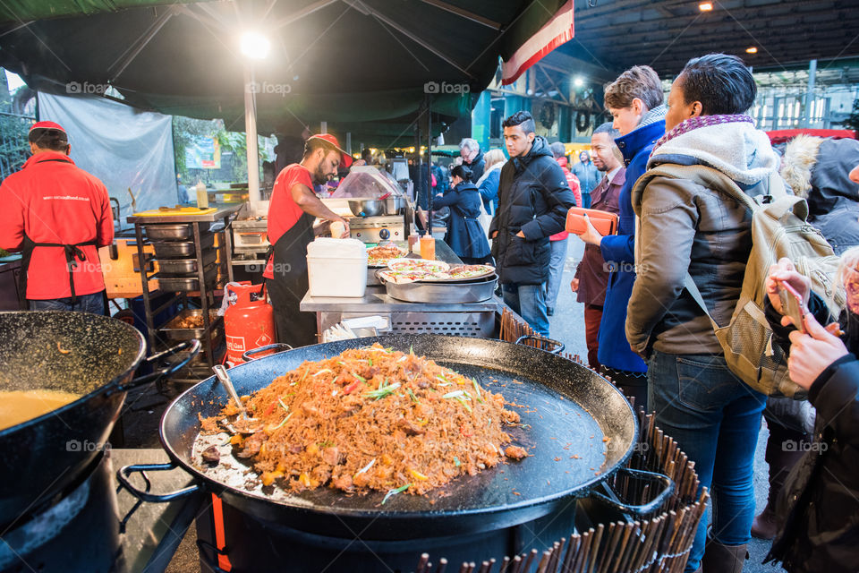 Food market at Borough Market in London. People waiting to buy fast food in a food stand.