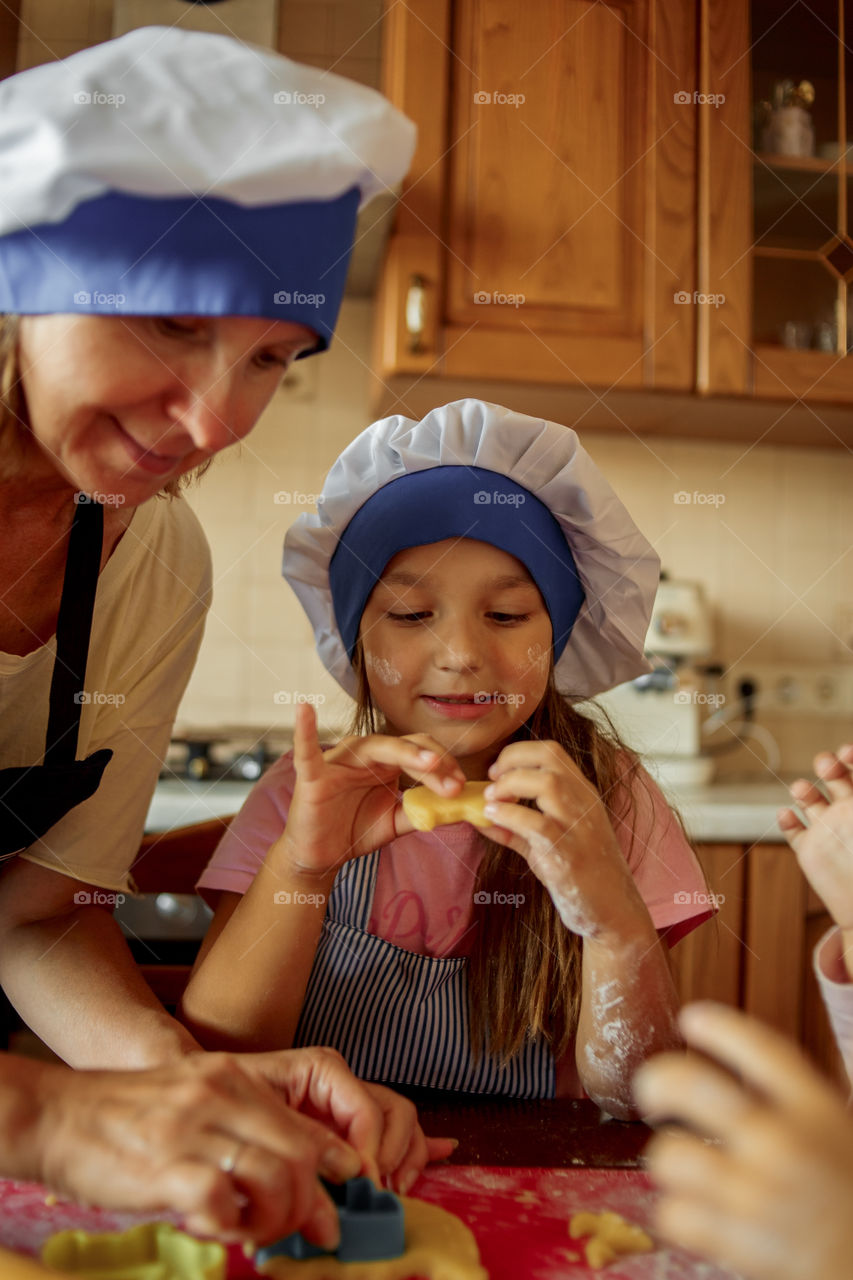 Little sisters with grandma cooking the biscuits 