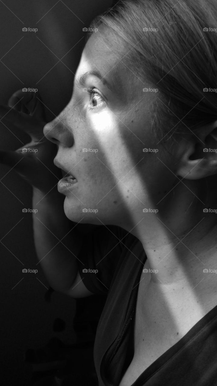 black and white photo of a girl looking out the window in horror
