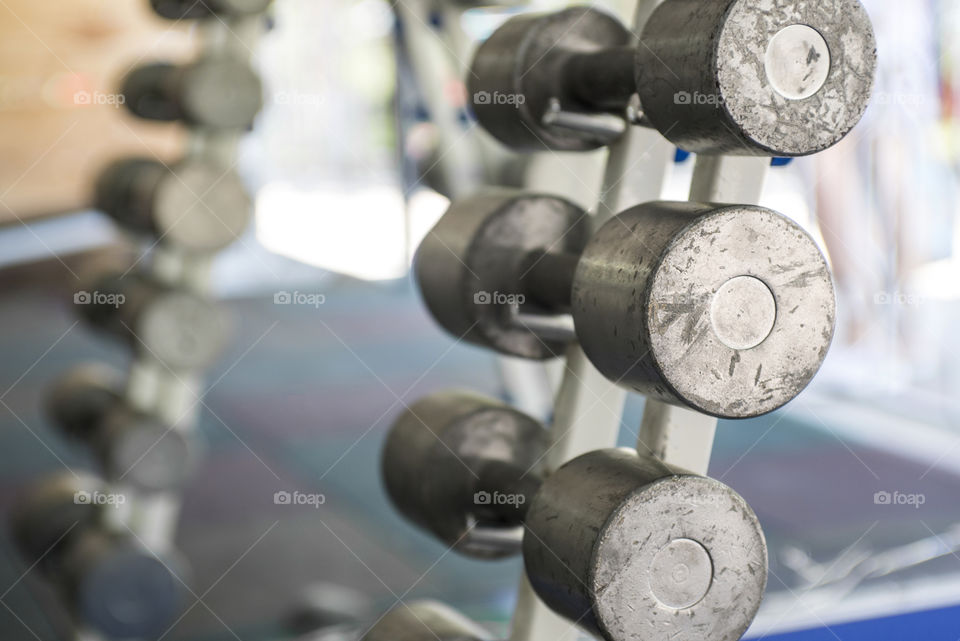 Rows of dumbbells in the gym. Dumbbell set. Close up many metal dumbbells on rack in sport fitness center