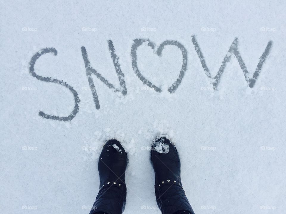 View from top of boots standing near the word snow written on snow