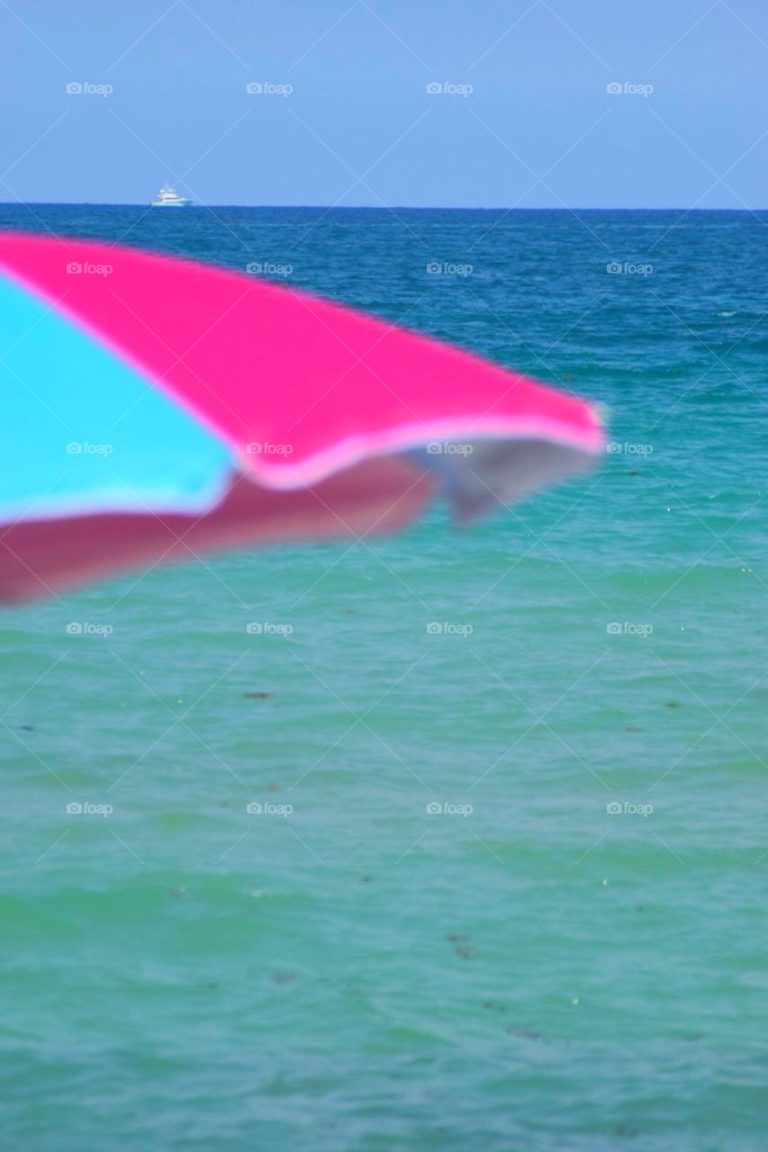 Brightly colored beach umbrella with Atlantic Ocean In back ground 