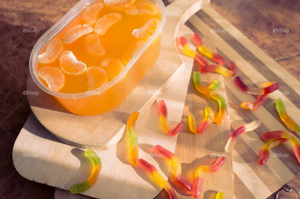 Delicious orange jelly with tangerine slices in a container and jelly worms.