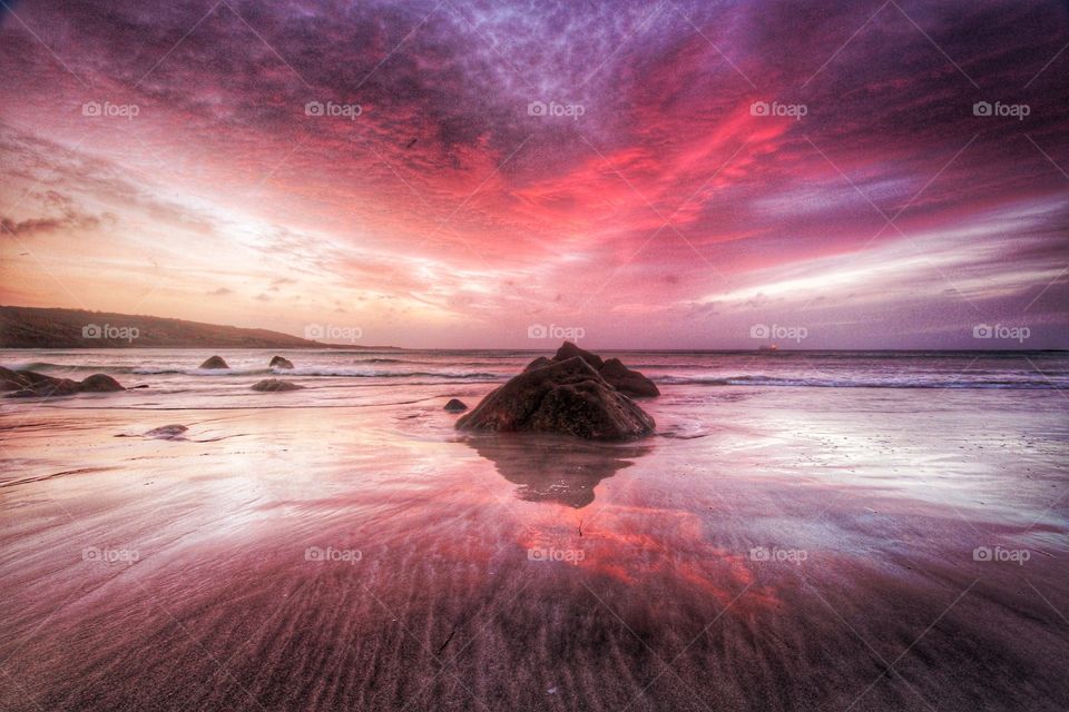 Red sky sunrise over a deserted beach in Cornwall, UK.