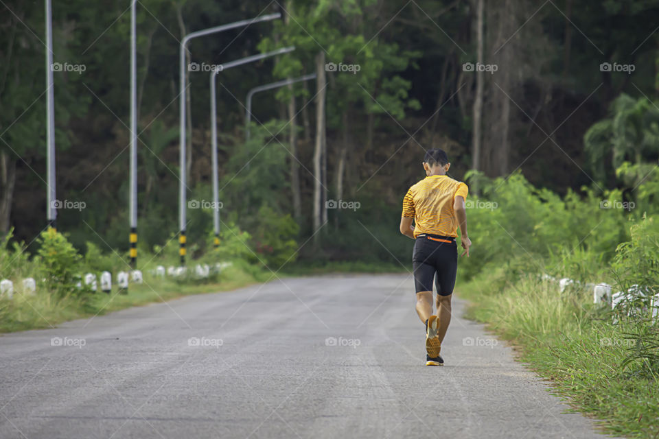 The men are running on the road Background light poles and trees.