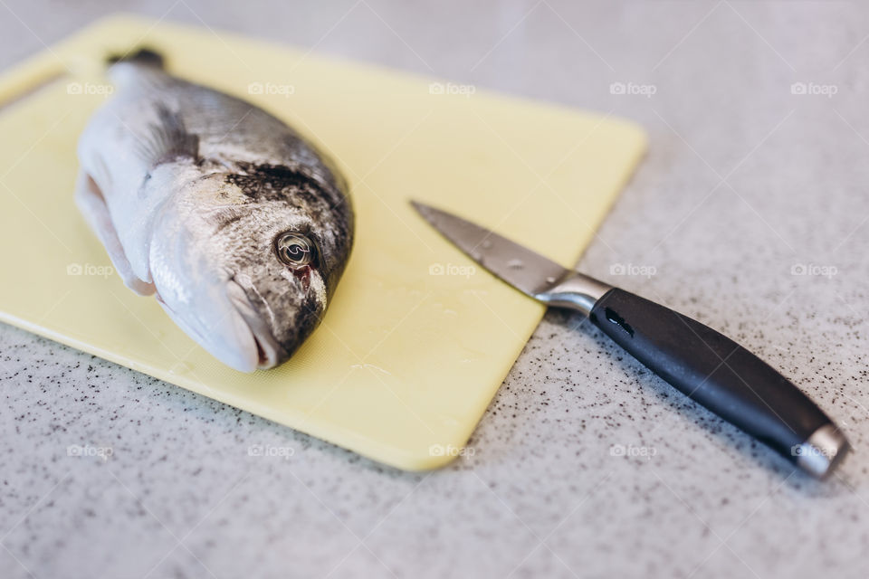 fish and knife on a yellow cutting board