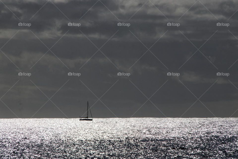 Sailing ship at atlantic ocean at sunset and storm clouds 